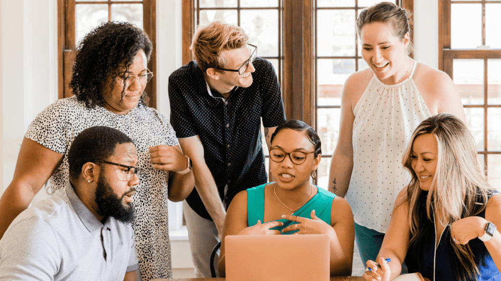 A group of people working around a laptop